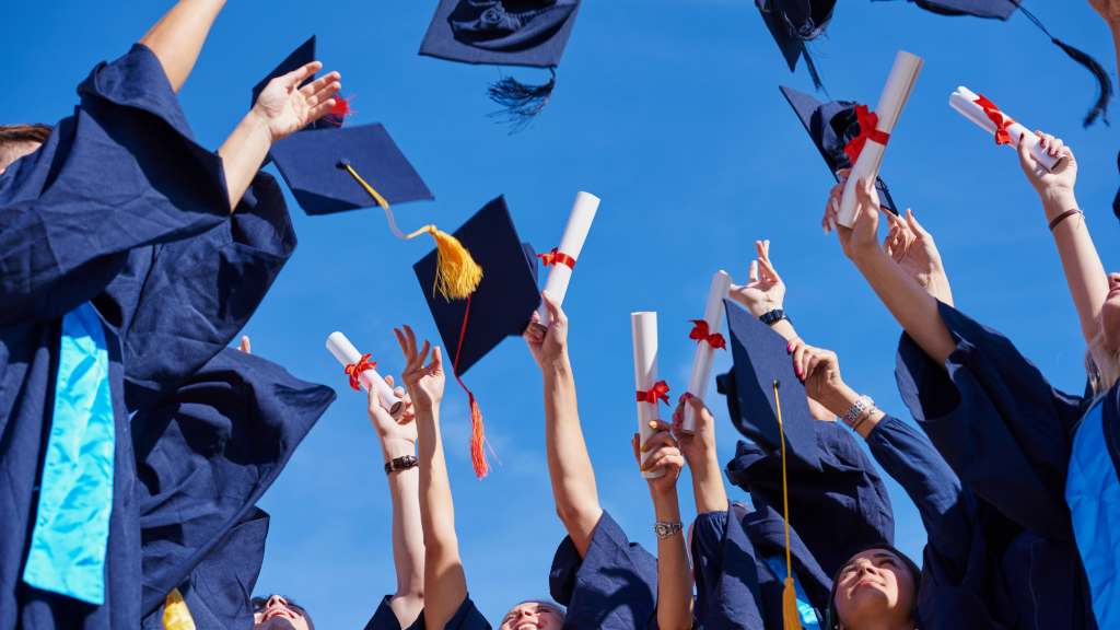 Graduates in maroon gowns toss their mortarboards into the air